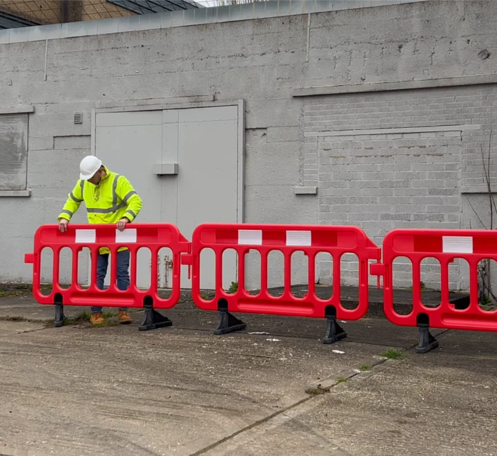 Person arranging a line of plastic barriers, demonstrating setup and alignment