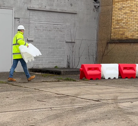 Person connecting multiple traffic separators, demonstrating assembly and setup